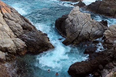人们冲浪海浪撞在岩石海岸白天

